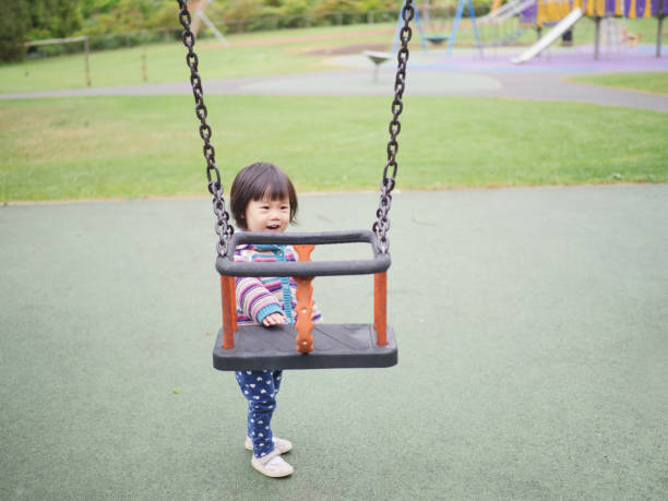 istock Cute Girl Standing By Swing In Playground 1047493434