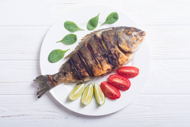 istock Fried fish dorado with lime , tomatoes and spinach 1047494256