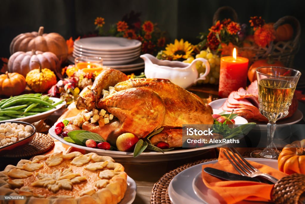 Thanksgiving turkey dinner Thanksgiving dinner. Roasted turkey garnished with cranberries on a rustic style table decoraded with pumpkins, vegetables, pie, flowers, and candles Thanksgiving - Holiday Stock Photo