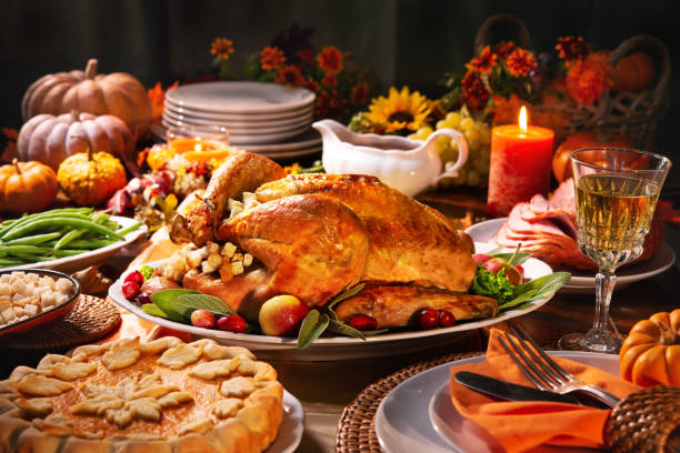 Thanksgiving turkey dinner Thanksgiving dinner. Roasted turkey garnished with cranberries on a rustic style table decoraded with pumpkins, vegetables, pie, flowers, and candles stuffing food photos stock pictures, royalty-free photos & images