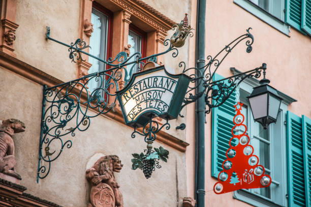 Traditional Maison Des Tetes Restaurant sign with Christmas ornates on half timbered building wall at street of Colmar, Alsace in north-eastern France.