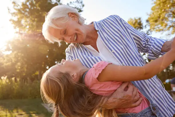 Grandmother Playing Game And Dancing With Granddaughter In Summer Park