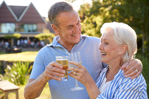 Senior Couple Enjoying Outdoor Summer Drink At Pub