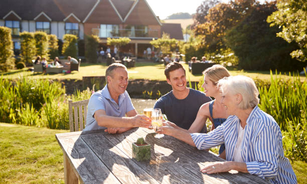 genitori con prole adulta che si godono un drink estivo all'aperto al pub - giardino di birra foto e immagini stock