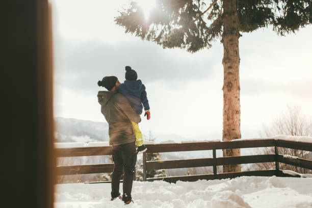 Photo of young father bonding with his son by taking him outdoors on a snowy winter day