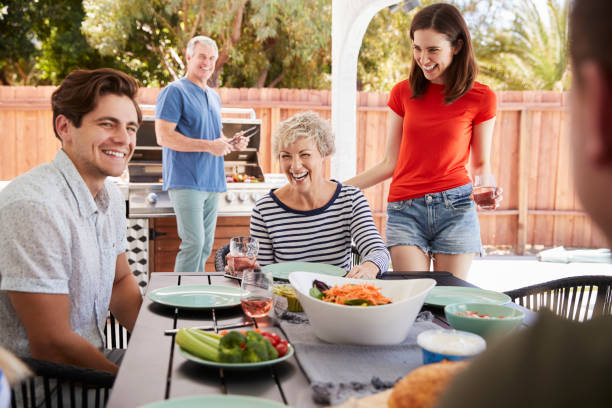Parents and adult children having a barbecue in the garden Parents and adult children having a barbecue in the garden happiness four people cheerful senior adult stock pictures, royalty-free photos & images