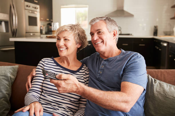 istock Senior couple sitting on couch watching television, close up 1047528130