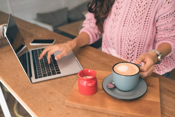 istock partial view of female freelancer working on laptop while sitting at table with smartphone and coffee cup in cafe 1047528388
