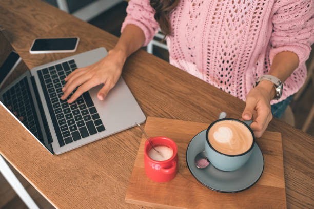 istock cropped image of female freelancer working on laptop while sitting at table with smartphone and coffee cup in cafe 1047528414