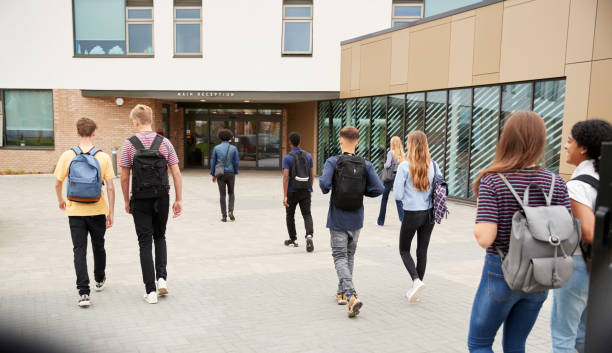achteraanzicht van middelbare scholieren lopen in college gebouw samen - ingang stockfoto's en -beelden