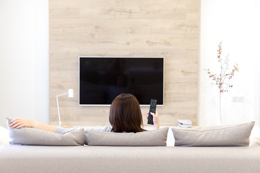 Young woman watching TV in the living room sitting on couch