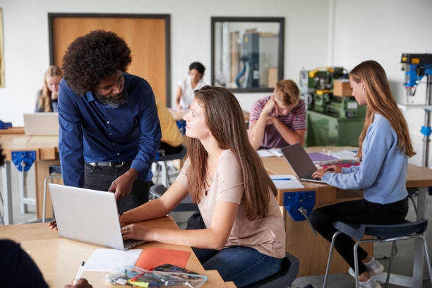 istock Teacher Talking To Female High School Student Sitting At Work Bench Using Laptop In Design And Technology Lesson 1047529150