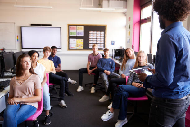 istock Male Teacher With Digital Tablet Teaching High School Computer Class 1047529918
