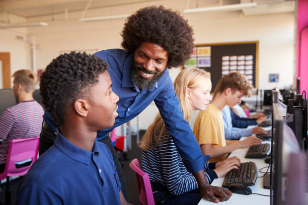 istock Teacher Helping Teenage Male High School Student Working In Computer Class 1047529990
