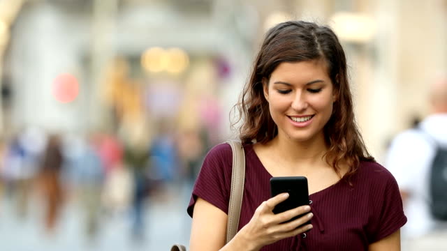 Woman walking and using a smart phone in the street