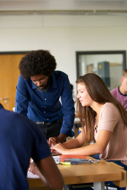 istock Teacher Talking To Female High School Student Sitting At Work Bench Using Laptop In Design And Technology Lesson 1047533150