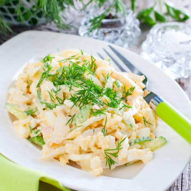 istock Salad with squid, egg and rice on a white plate, selective focus 1047533626