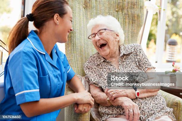 Ältere Frau Sitzt Im Stuhl Und Lachen Mit Krankenschwester Im Altenheim Stockfoto und mehr Bilder von Alter Erwachsener