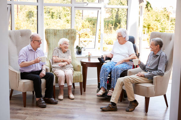 mężczyźni i kobiety mieszkańcy siedzą na krzesłach i rozmawiają w salonie domu emerytalnego - one person lifestyles 80 plus years indoors zdjęcia i obrazy z banku zdjęć