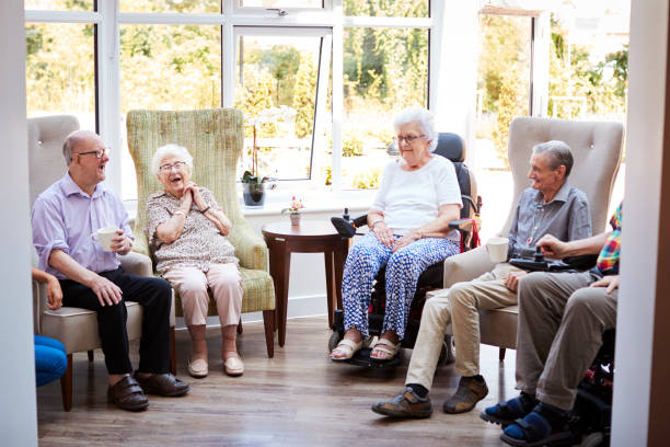 residenti maschi e femmine seduti su sedie e parlando nel salotto della casa di riposo - lifestyles residential structure community house foto e immagini stock