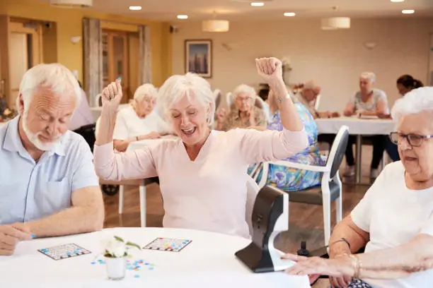 Senior Woman Winning Game Of Bingo In Retirement Home