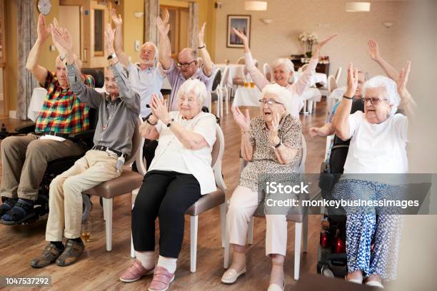 Group Of Seniors Enjoying Fitness Class In Retirement Home Stock Photo - Download Image Now