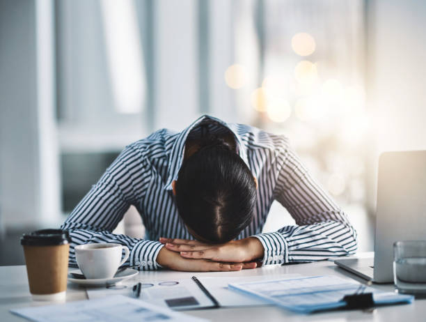 Dreamland is better than all these deadlines Shot of a young businesswoman lying with her head down on a desk in an office mental burnout photos stock pictures, royalty-free photos & images