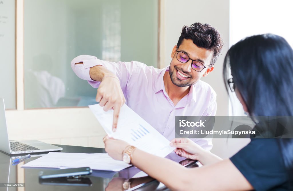 Indian investment expert Indian man showing fact sheet with graphs to a woman India Stock Photo