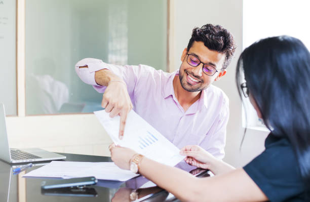 Indian investment expert Indian man showing fact sheet with graphs to a woman Loan stock pictures, royalty-free photos & images