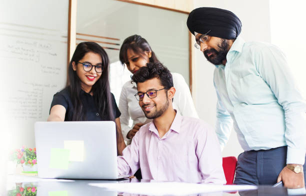 il team indiano lavora insieme e guarda su uno schermo di laptop - india foto e immagini stock