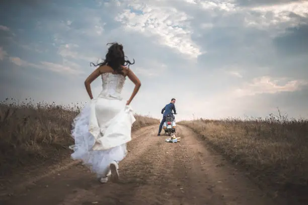 Bride running towards the bridegroom who is waiting her on the vespa motorbike to go away somewhere