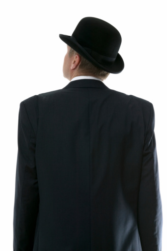 Businessman in a bowler hat looking up to the future. Rear view.