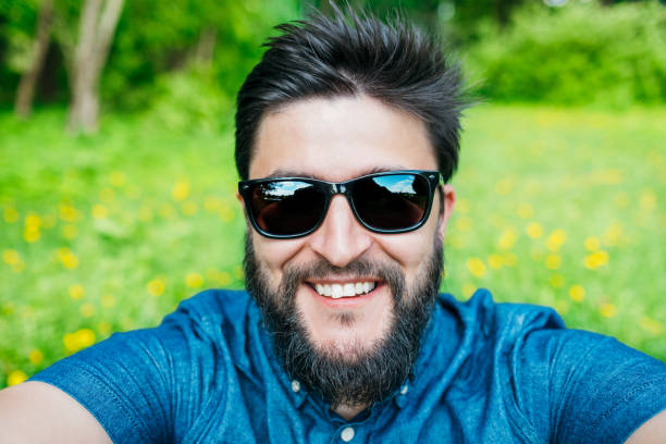Man taking selfie in the forest. Holding phone by two hands