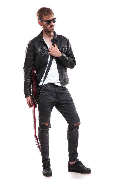 young blonde star holding his electric guitar and looking to side while standing on white background