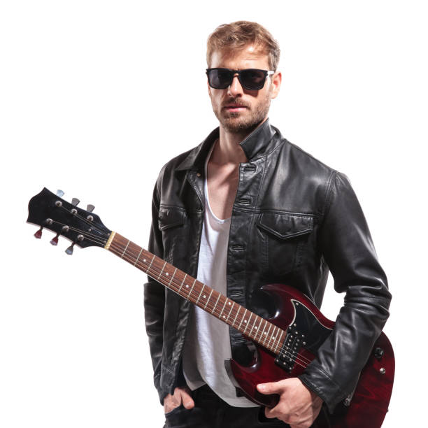 istock attractive man standing with hand in pocket while holding guitar 1047575066