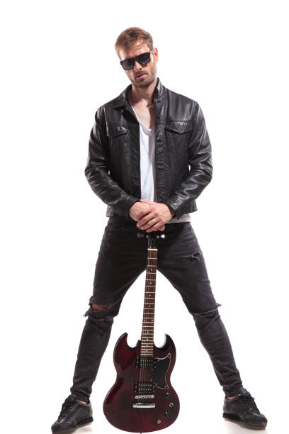 istock handsome rock star posing while holding his guitar 1047575144