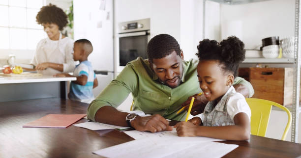 Let's first see what homework you have Cropped shot of a young handsome father helping his daughter with her schoolwork at home homework stock pictures, royalty-free photos & images