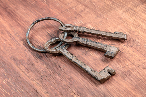 A photo of old keys on a ring, on a dark rustic texture with copy space