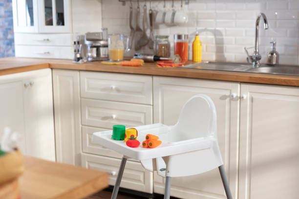 Empty highchair in a clean kitchen Empty highchair in a clean kitchen with colorful toys high chair stock pictures, royalty-free photos & images