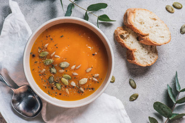 top view of bowl with pumpkin cream soup with seeds and bread on table top view of bowl with pumpkin cream soup with seeds and bread on table pumpkin soup photos stock pictures, royalty-free photos & images