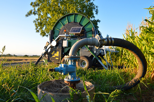 An ecological agricultural irrigation system with a big hose reel and photovoltaic solar panel at dawn