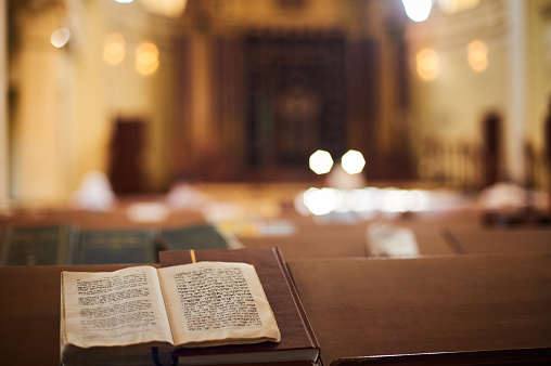 Interior de la sinagoga ortodoxa con libro abierto en el idioma hebreo en primer plano. enfoque selectivo photo