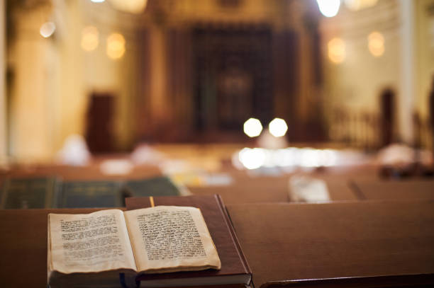 Inside of Orthodox Synagogue with open book in the Hebrew language in the foreground. selective focus stock photo