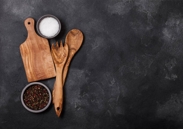 istock Olive wood kitchen utensils with chopping board stone table background. Top view. Space for text 1047609262