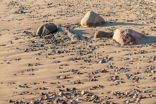 pebbles and big stones on sand beach by summer evening