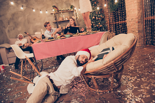 Beautiful attractive stylish classy elegant cheerful funky people sitting at dinner table with martini, guys sleeping in santa claus hats, house chill-out