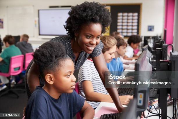 Foto de Professor Ajudando A Aluna Linha De Estudantes Do Ensino Médio Trabalhando Em Telas Na Aula De Informática e mais fotos de stock de Professor