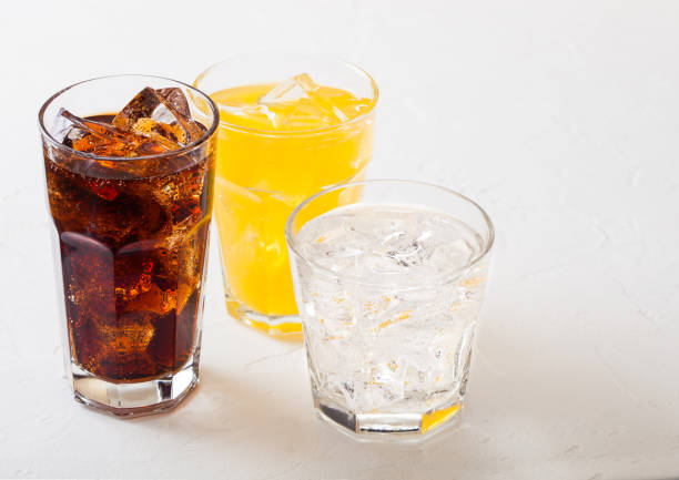 istock Glasses of soda drink with ice cubes and bubbles on stone kitchen table background. Cola and orange lemonade soda 1047617080