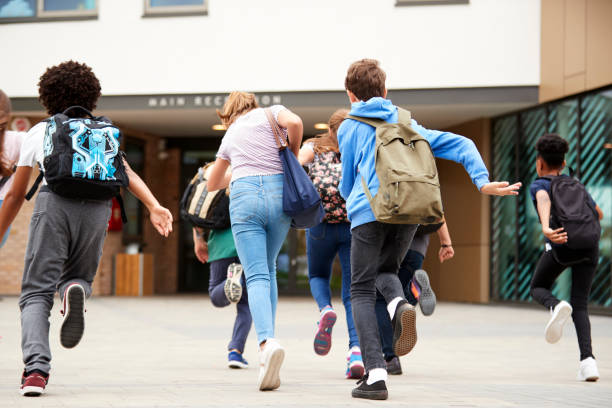 istock Group Of High School Students Running Into School Building At Beginning Of Class 1047617206