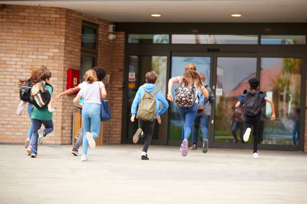 istock Group Of High School Students Running Into School Building At Beginning Of Class 1047617214